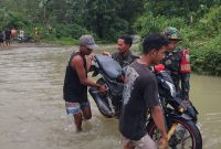Babinsa Serda Candra Kirana Sam bersama dengan warga bantu angkat motor saat kali Wae Galang Banjir di Desa Golo Ketak kecamatan Boleng pada, Kamis 15/01/2026