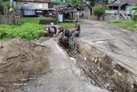 Babinsa Koramil 1630-01 Komodo ya g bertugas di Kecamatan Boleng, bantu warga memperbaiki Deker yang rusak menuju ke Pasar Terang